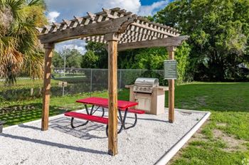 A picnic area with a red table and a wooden pergola.